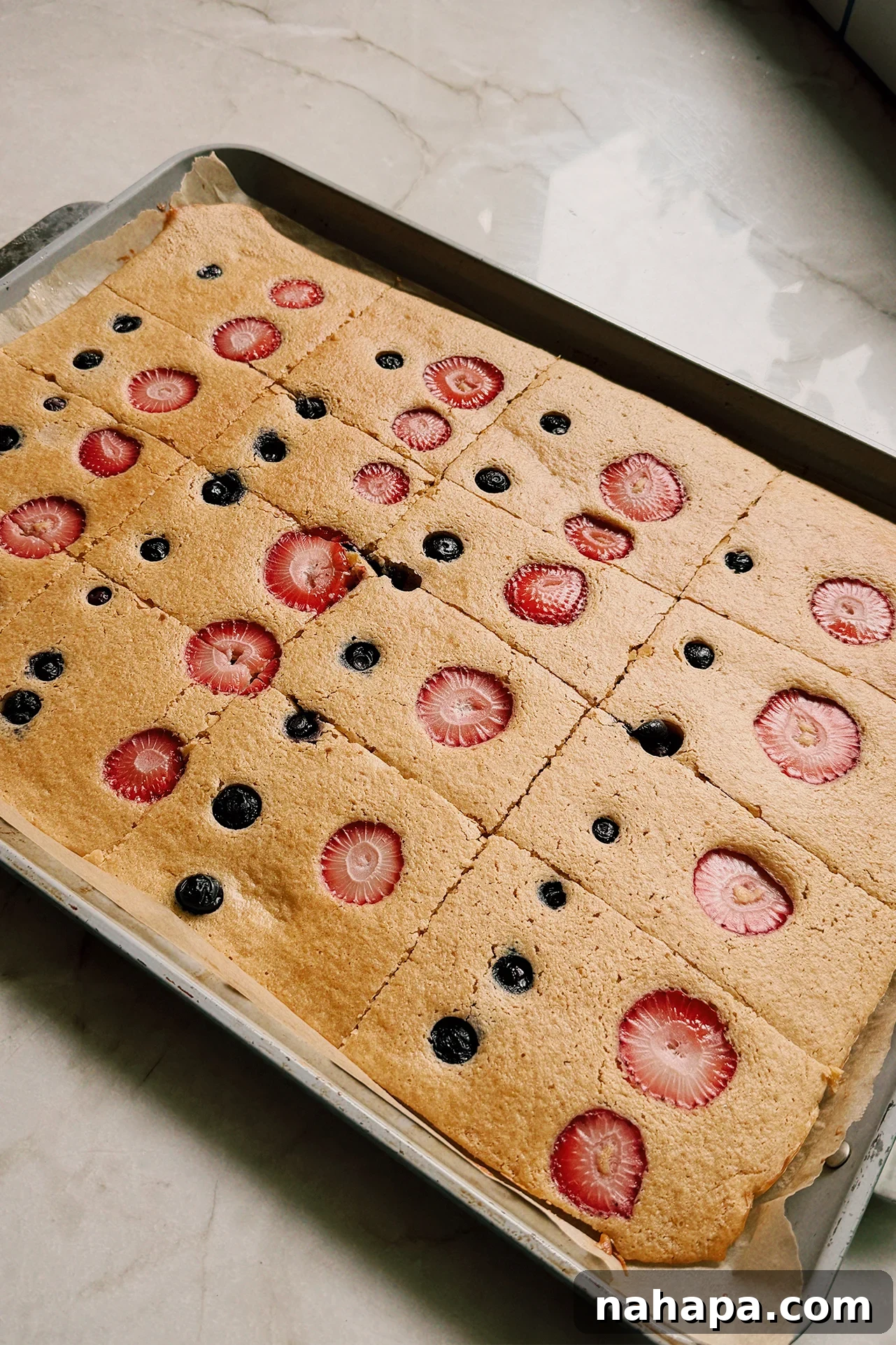 Sheet pan pancakes topped with berries on a large sheet pan
