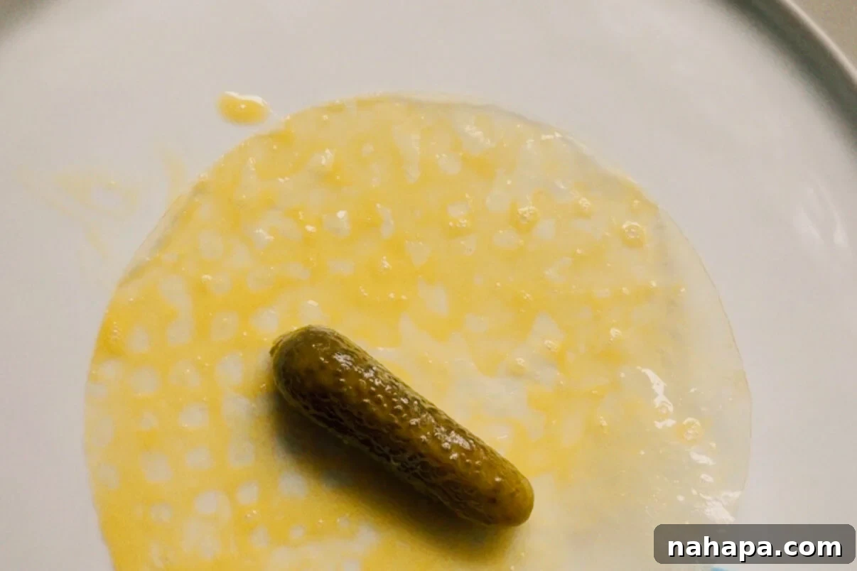 A pickle in the center of rice paper on a plate