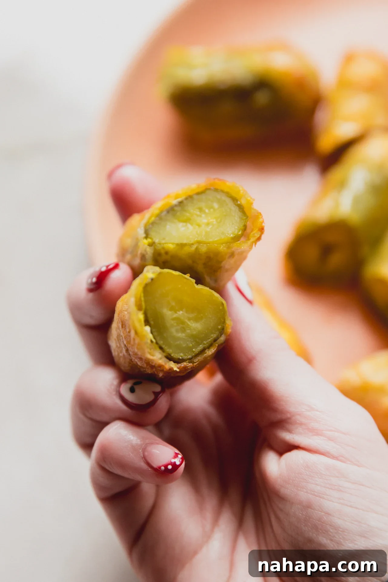 Rice paper fried pickles cut in half and being held