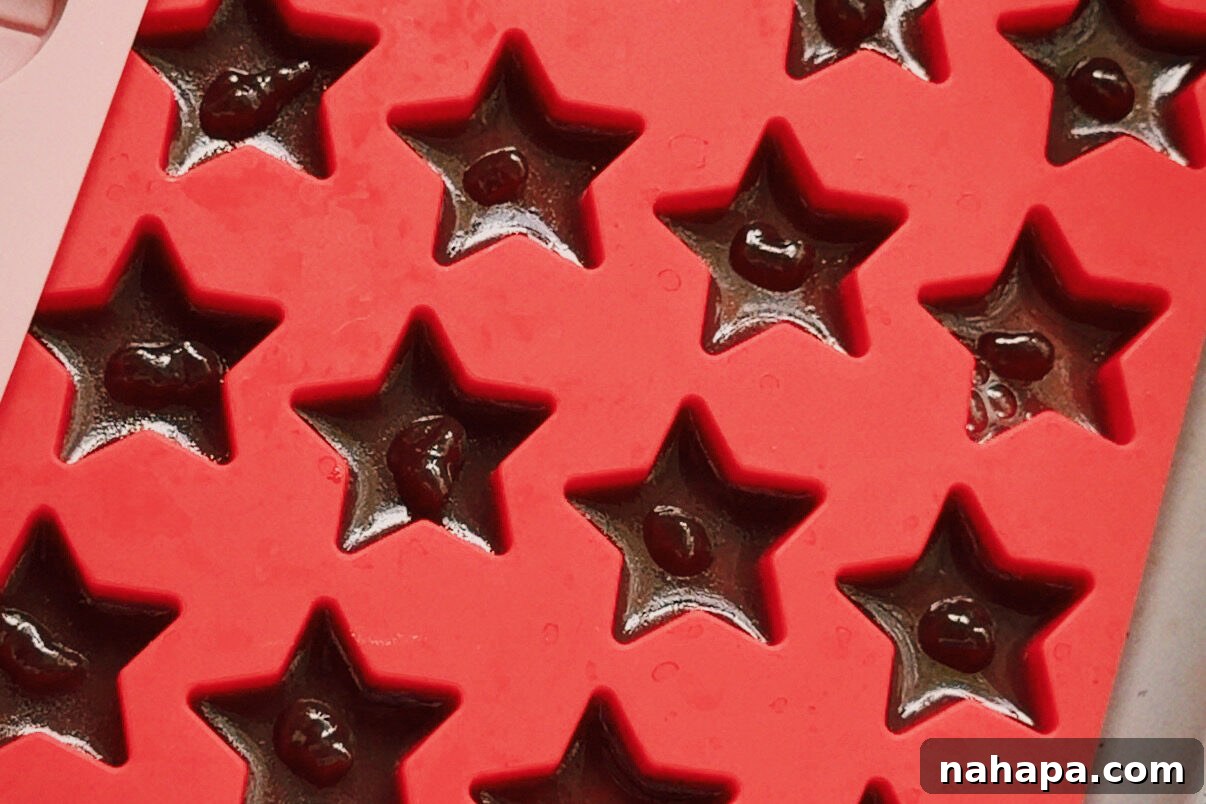 The star mold with the grape jam dotting each star mold of apple gelatin.