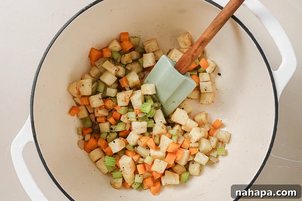 A Dutch oven with cut up veggies and garlic being sauted.